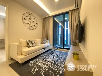 Chic modern living room with plush sofa, stylish rug, and sleek wall-mounted TV, leading to a cozy balcony with natural light.