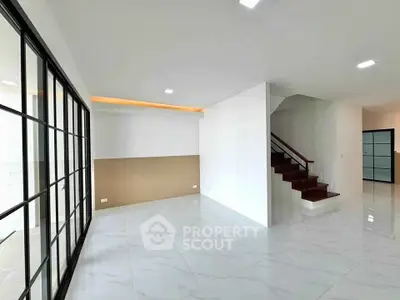 Spacious modern living room with elegant staircase and sleek glass doors
