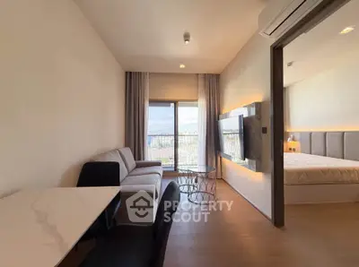 Modern living room with open layout and bedroom view, featuring stylish furniture and natural light.