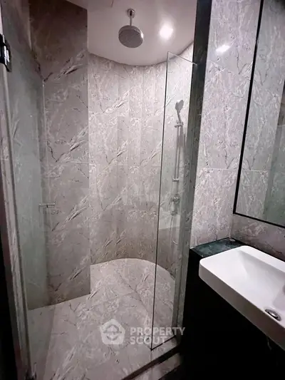 Luxurious modern bathroom with marble tiles and glass shower enclosure