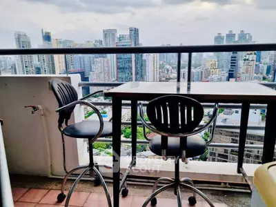 Stunning cityscape view from a high-rise balcony with modern seating, perfect for urban living.