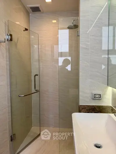 Modern bathroom with glass shower enclosure and sleek sink design.