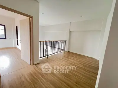 Spacious open area with wooden flooring and railing, perfect for versatile use.