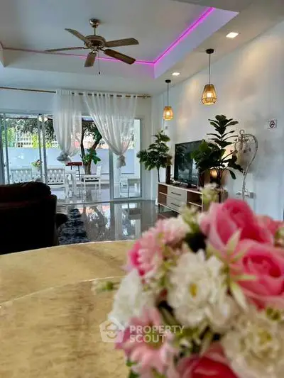 Spacious living room with modern decor and garden view, featuring elegant lighting and ceiling fan.