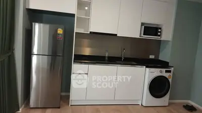 Modern kitchen with sleek appliances including fridge, microwave, and washing machine.