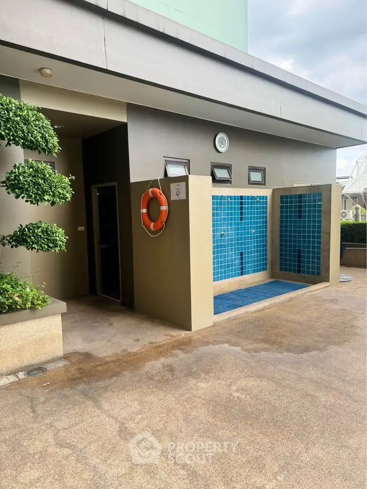 Modern outdoor shower area with blue tiles and safety equipment
