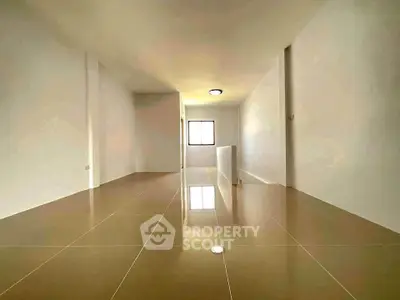 Spacious empty room with glossy tiled flooring and bright natural light.