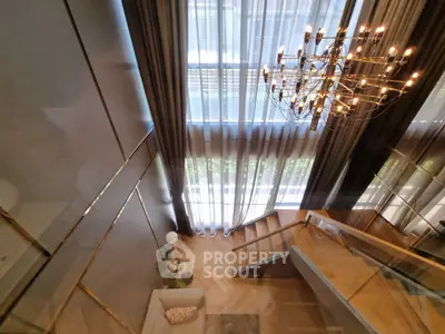 Luxurious modern living room with grand chandelier and elegant staircase