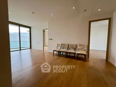 Spacious modern living room with wooden flooring and large windows in a luxury apartment.