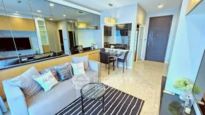 Modern living room with elegant decor and mirrored wall, featuring cozy seating and dining area.