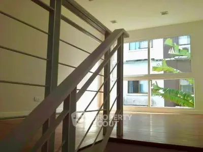 Modern interior with sleek staircase and large windows offering natural light and urban views.