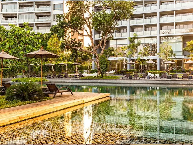 Luxurious apartment complex with serene pool and lush greenery, perfect for relaxation and modern living.
