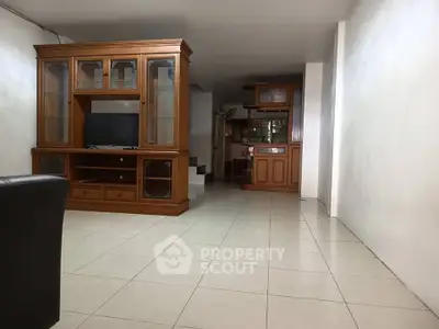 Spacious living room with wooden entertainment center and tiled flooring