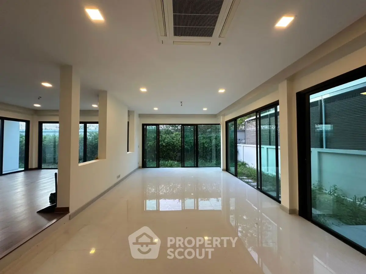 Spacious modern living room with large windows and garden view, perfect for natural light lovers.