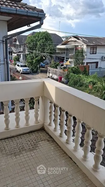 Charming balcony with classic railing overlooking a suburban neighborhood street view.