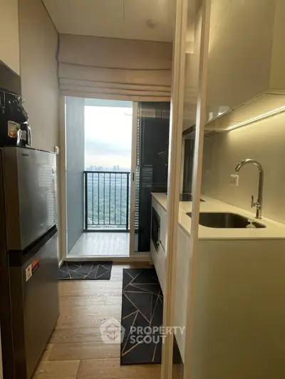 Modern compact kitchen with balcony view in high-rise apartment