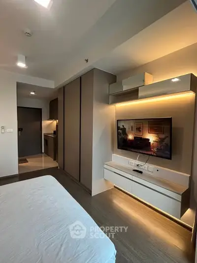 Modern bedroom with sleek design and built-in TV unit, featuring ambient lighting.