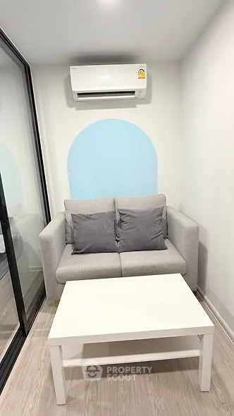 Cozy small living room with modern sofa and air conditioning unit.