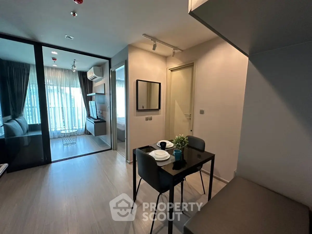 Modern apartment interior with dining area and cozy living space, featuring sleek design and natural light.