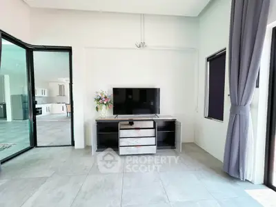 Modern living room with sleek TV stand and large windows, offering a bright and airy atmosphere.