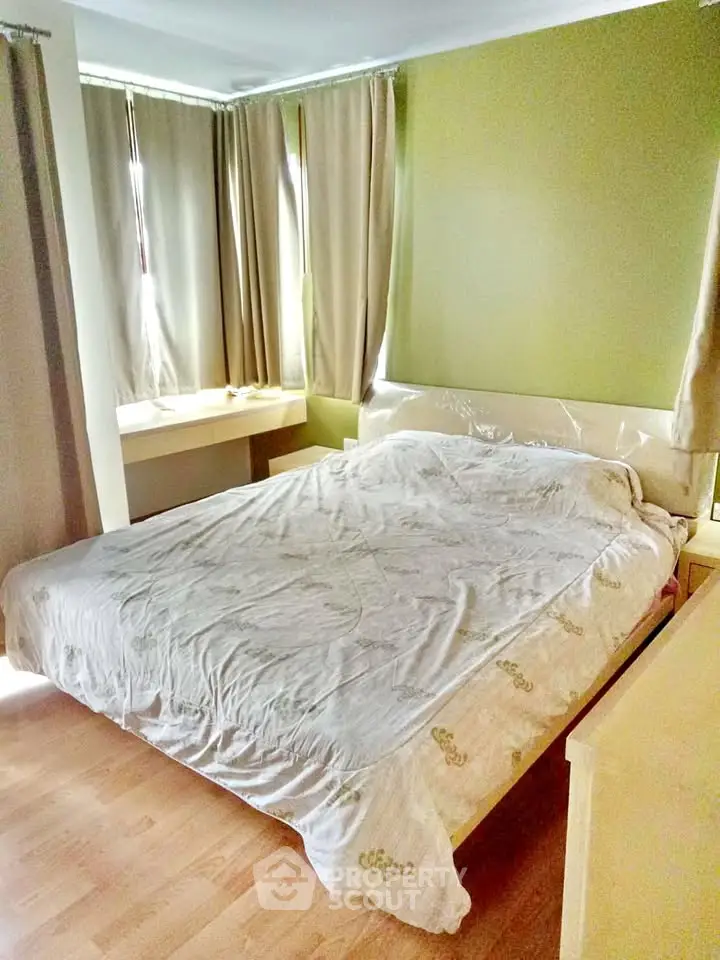Cozy bedroom with natural light and wooden flooring, featuring a comfortable bed and stylish curtains.