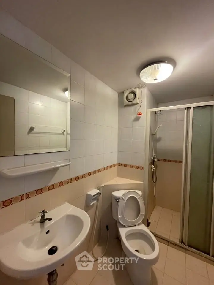 Modern bathroom with shower, toilet, and sink in a well-lit space.