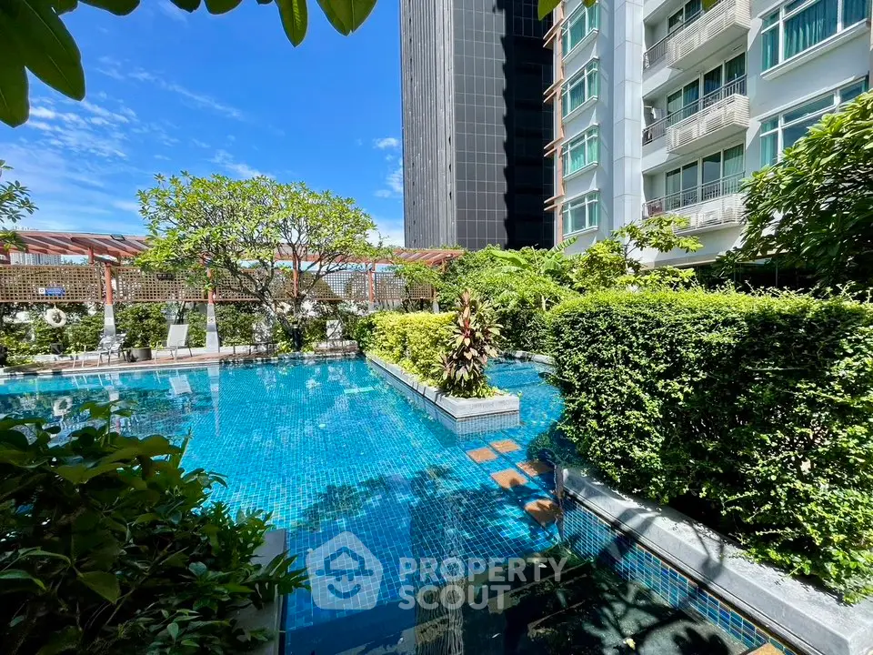 Luxurious residential pool area with lush greenery and modern building backdrop.