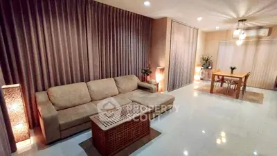 Spacious living room with elegant lighting and cozy dining area, perfect for modern living.
