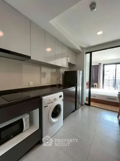 Modern kitchen with washing machine and sleek appliances in open layout apartment.