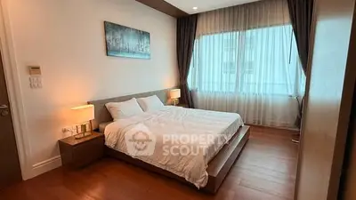 Spacious bedroom with elegant decor and large window for natural light.