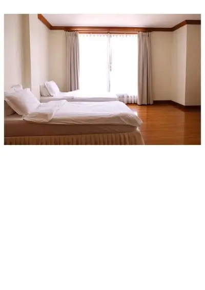 Spacious bedroom with two beds and elegant wooden flooring, perfect for comfort and relaxation.