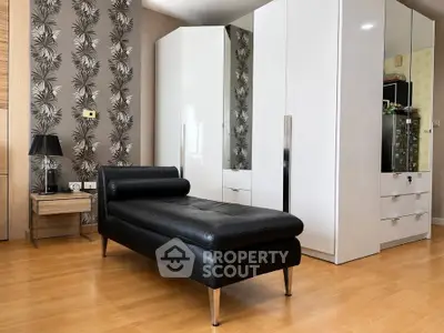 Stylish bedroom with modern black chaise lounge and sleek white wardrobes