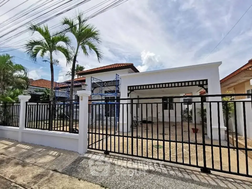 Charming single-story home with gated entrance and palm trees, perfect for family living.