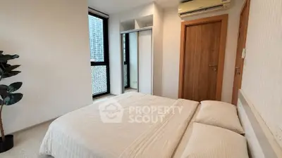 Modern bedroom with large window and built-in closet in urban apartment.