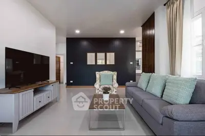 Modern living room with stylish decor, featuring a cozy sofa, elegant armchair, and sleek TV setup.