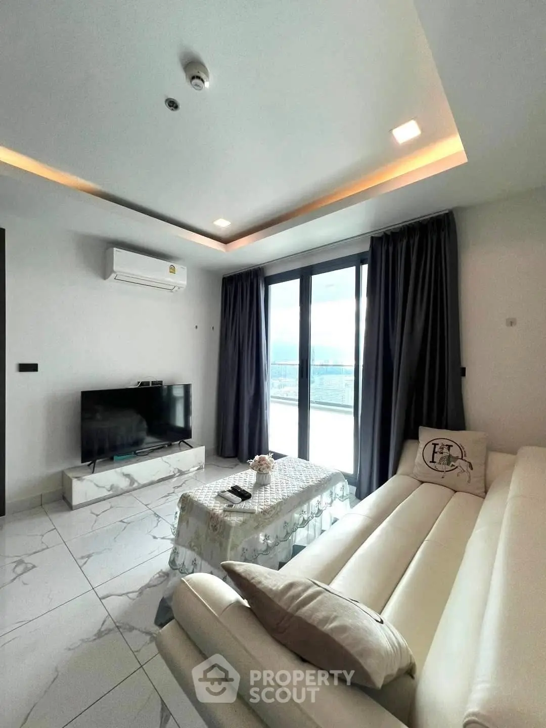 Modern living room with sleek white sofa and large windows offering natural light.