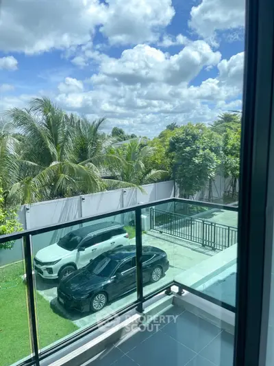 Stunning balcony view with lush greenery and parked cars under a clear blue sky.