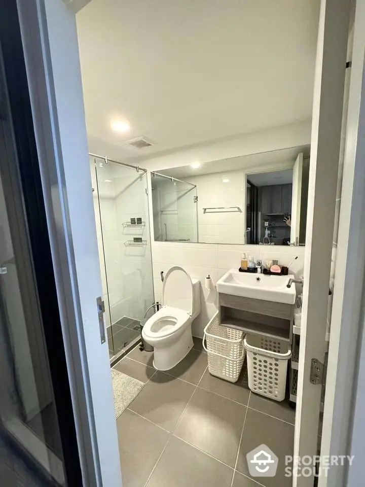 Modern bathroom with glass shower and sleek fixtures in contemporary apartment.