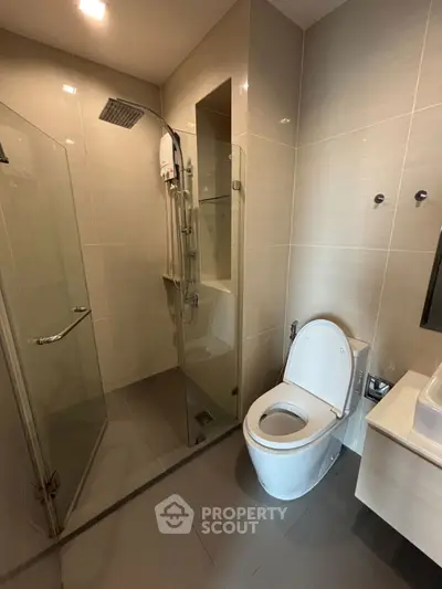 Modern bathroom with glass shower and sleek fixtures in contemporary apartment.