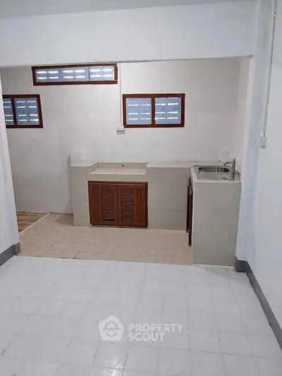 Minimalist kitchen with closed layout and dual sinks in a bright, tiled space.