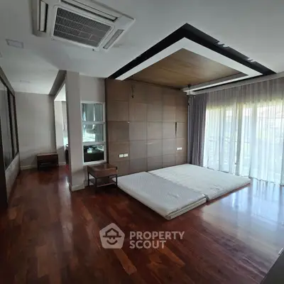 Spacious bedroom with wooden floors and large windows for natural light.