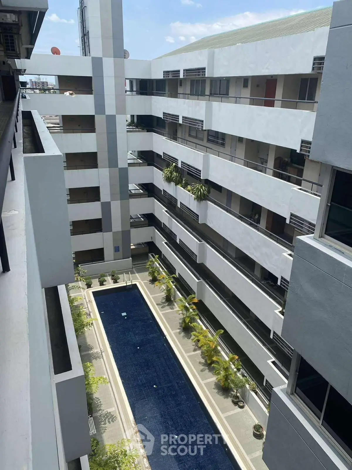 Modern apartment building with central courtyard pool and lush greenery.