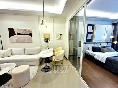 Modern open-plan living room with elegant decor and adjacent bedroom view.