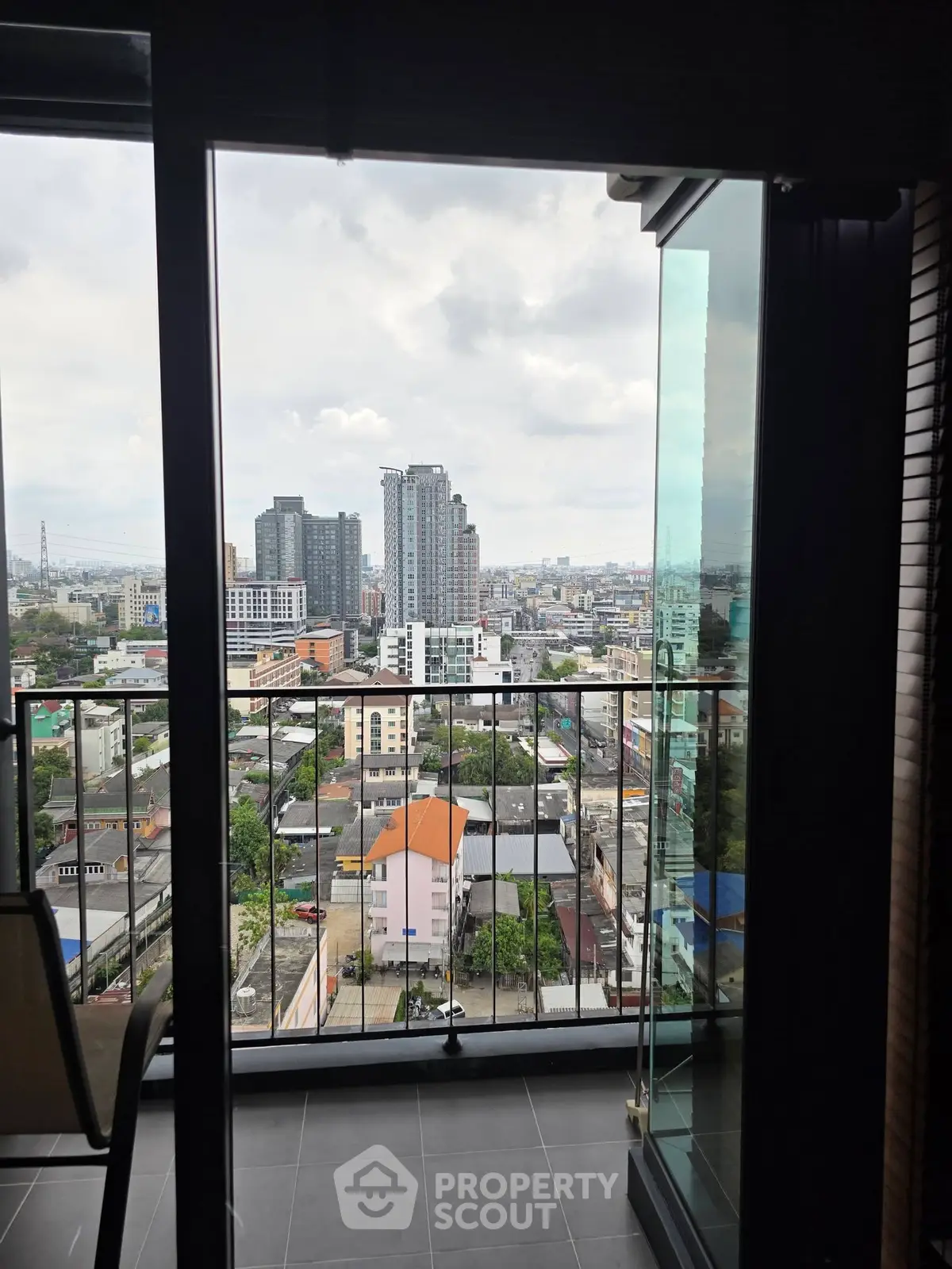 Stunning cityscape view from a modern balcony with glass doors, perfect for urban living.
