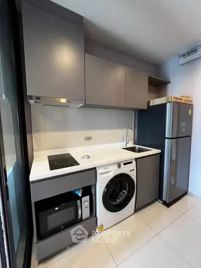 Modern compact kitchen with sleek appliances and integrated washing machine in stylish apartment.