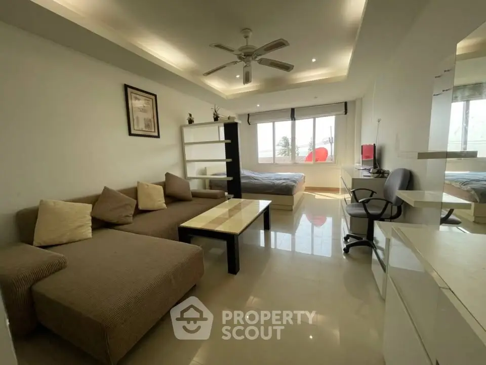 Modern studio apartment with cozy living area and large window view.