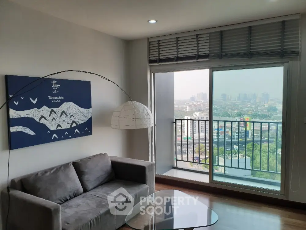 Spacious living room with modern furnishings, large windows offering panoramic city views, and abundant natural light.