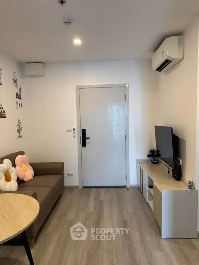 Modern living room with stylish decor and air conditioning, featuring a cozy sofa and entertainment unit.