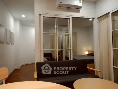 Modern apartment interior with cozy living room and bedroom view, featuring stylish furniture and warm lighting.