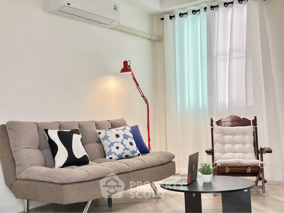 Stylish living room with modern sofa, rocking chair, and red floor lamp.